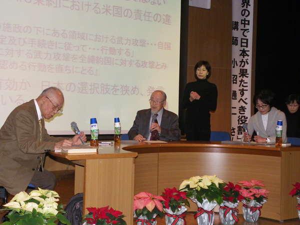 プロジェクタースクリーンの前に置かれたテーブルに座りマイクを持ち話をしている小沼先生と河合先生の写真